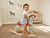Child riding a wooden rocking horse in a room with framed horse pictures on the wall.