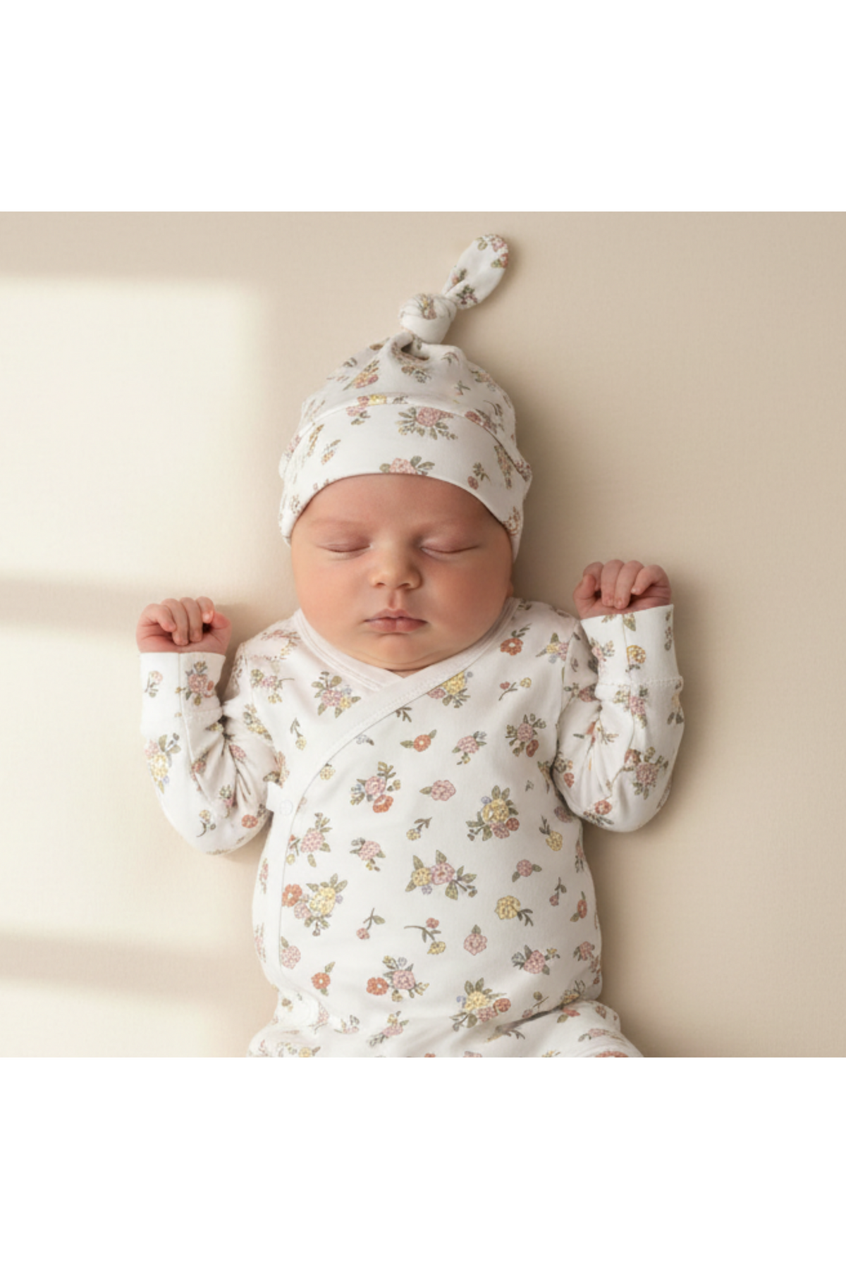A peaceful sleeping baby is wearing a floral-patterned organic cotton kimono gown and matching knotted hat. The soft, breathable fabric is perfect for gentle nighttime comfort.