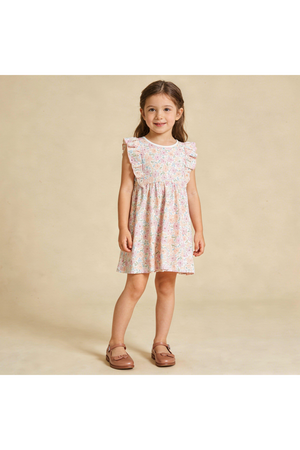 A young girl models a playful flutter dress with a floral pattern in soft pastel colors. The dress features ruffled sleeves and is made from organic materials.