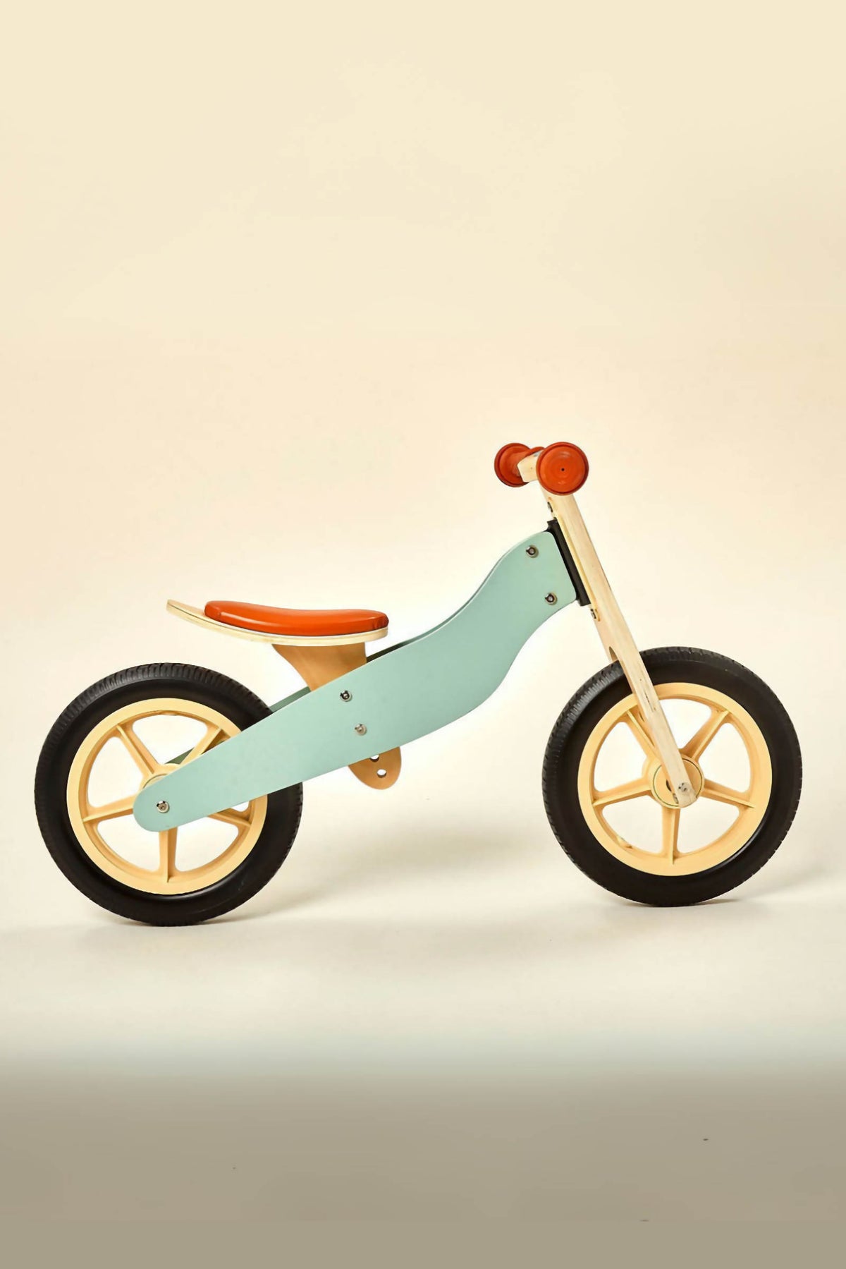 A wooden balance bike features a light blue frame, orange seat, and black wheels, designed for children ages 2 to 4.