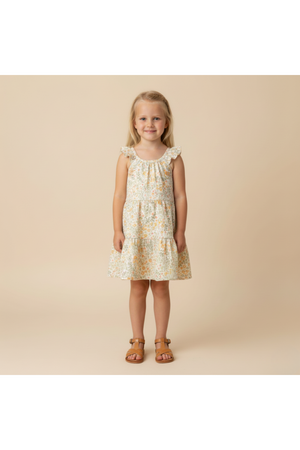 A young girl models a floral organic cotton dress with ruffle straps and a tiered design, set against a neutral background.