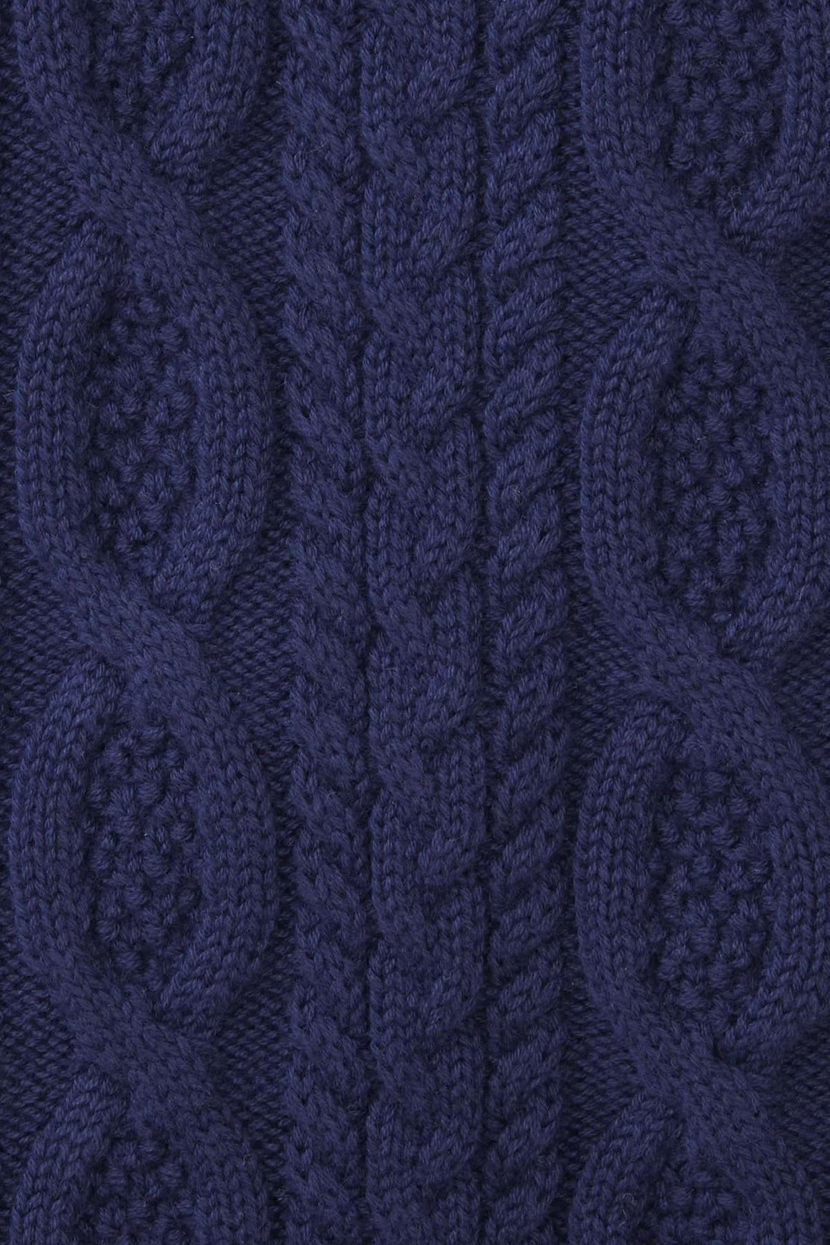 Close-up of a navy blue cable knit sweater featuring intricate patterns and textures, made from 100% organic cotton.