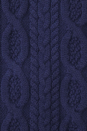 Close-up of a navy blue cable knit sweater featuring intricate patterns and textures, made from 100% organic cotton.