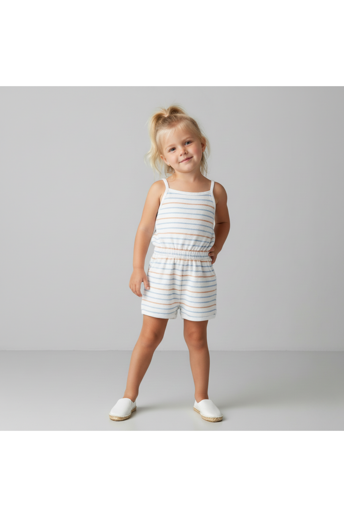 A young girl poses wearing a soft, organic cotton tank romper featuring blue and orange stripes. The romper has a comfortable, pull-on style, perfect for warm-weather activities.