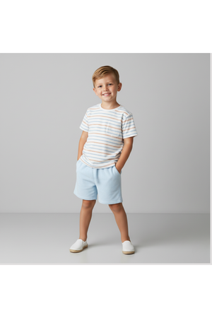 A young boy stands confidently with his hands in the pockets of light blue shorts, wearing a striped organic cotton tee.