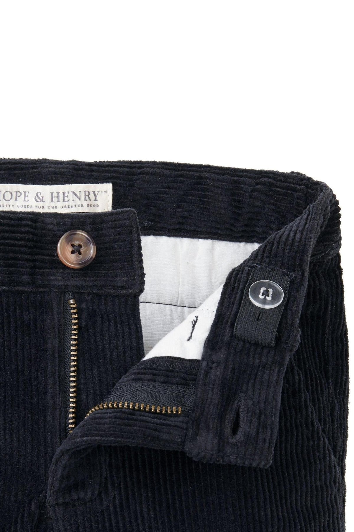 Close-up of black corduroy pants featuring a zipper, faux horn button, and organic cotton label from Hope & Henry.
