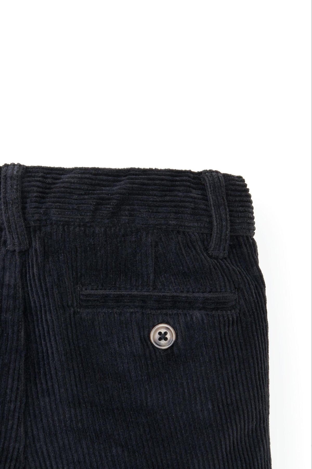 Close-up of black organic cotton stretch corduroy pants featuring a faux horn button and textured fabric.