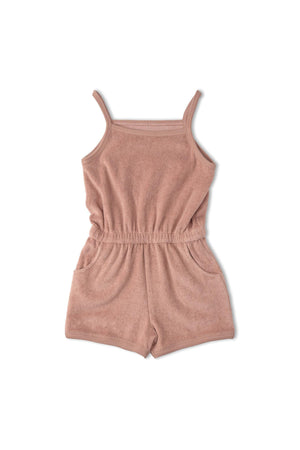 A clay-colored organic tank romper made from soft terry fabric features thin straps and an elastic waistband with pockets. Ideal for warm-weather outings, this sustainable piece is designed for comfort.