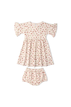 Light pink dress with a cherry print, featuring short ruffled sleeves and a gathered skirt, paired with matching bloomers. Made from soft, breathable organic cotton for comfort and play.