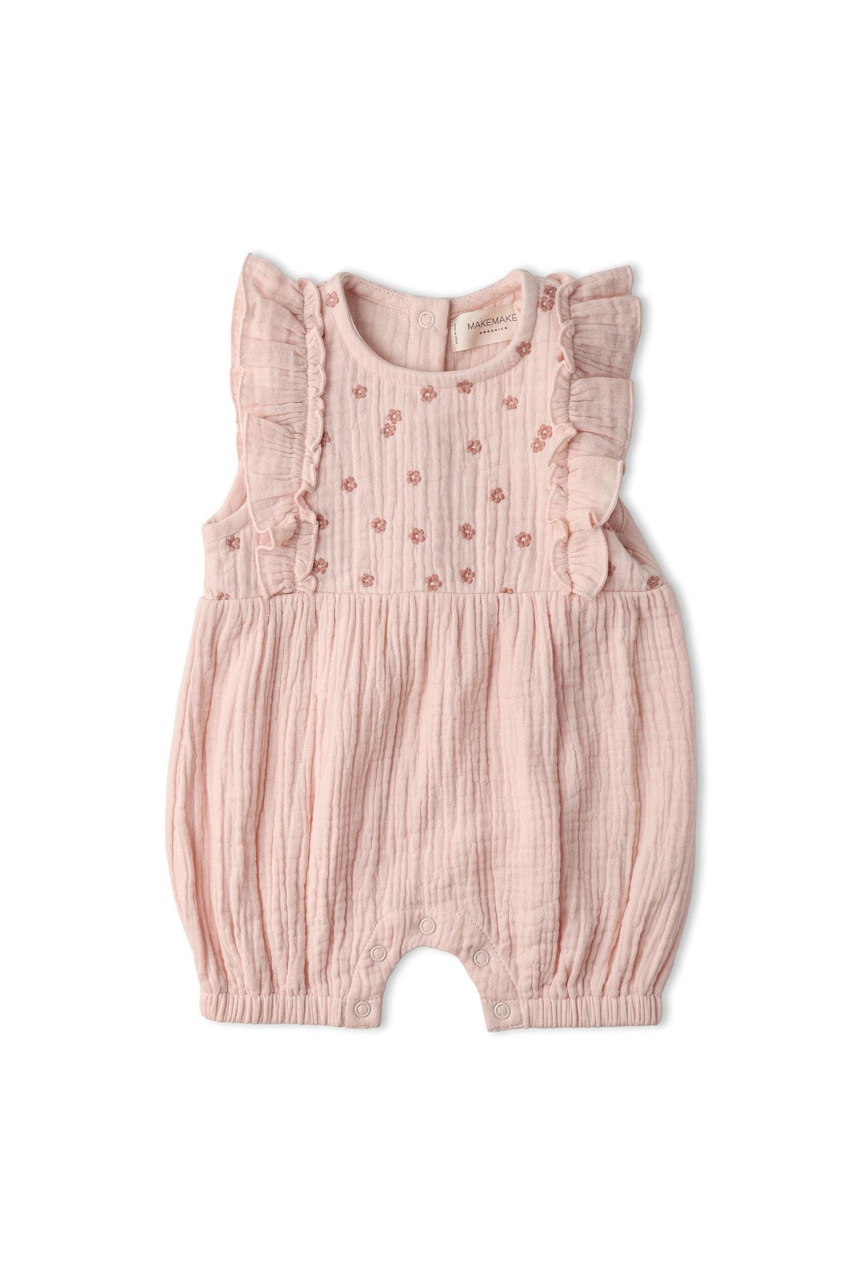 A blush pink organic cotton romper features delicate ruffle accents and intricate floral embroidery. This lightweight, airy garment is perfect for warm-weather days and designed for comfort.