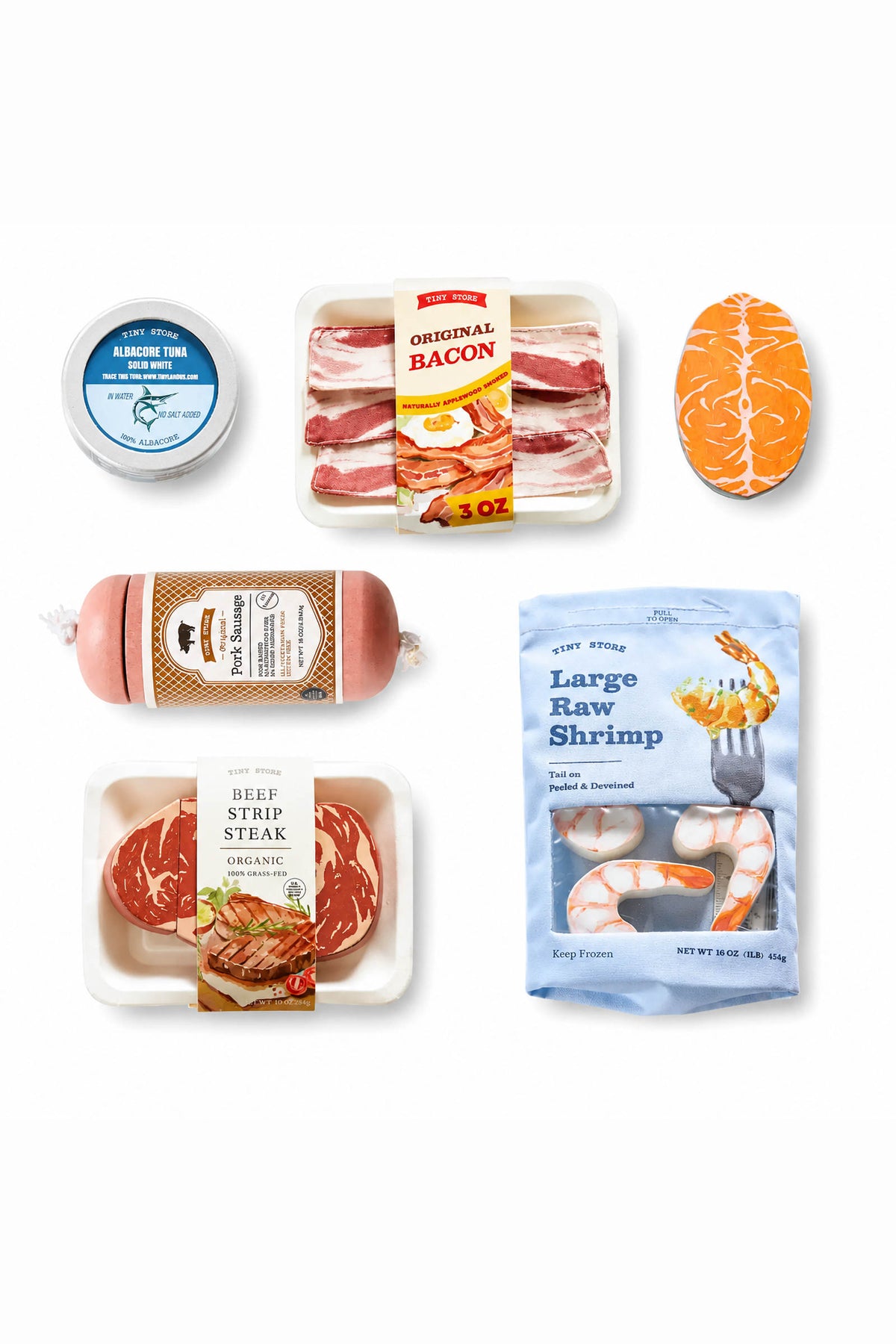 A colorful assortment of wooden play food items includes bacon, steak, shrimp, and tuna, all packaged in realistic containers.