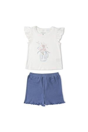 A sleeveless white top with flutter sleeves features a floral design, paired with blue shorts that have a ruffled hem. This organic cotton set is perfect for warm weather.