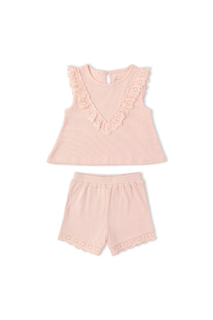 A blush pink ruffle top features a V-neck design with lace trim, paired with matching shorts that have scalloped edges. This organic cotton set is perfect for comfortable, stylish play.