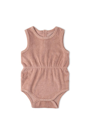 A soft clay-colored romper made from organic cotton features a gently gathered waist, ideal for warm-weather wear. This lightweight piece is perfect for sunny day adventures for little ones.