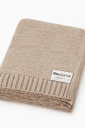 Beige knit blanket with a ribbed edge and a Bleu La La Organics label, folded neatly.