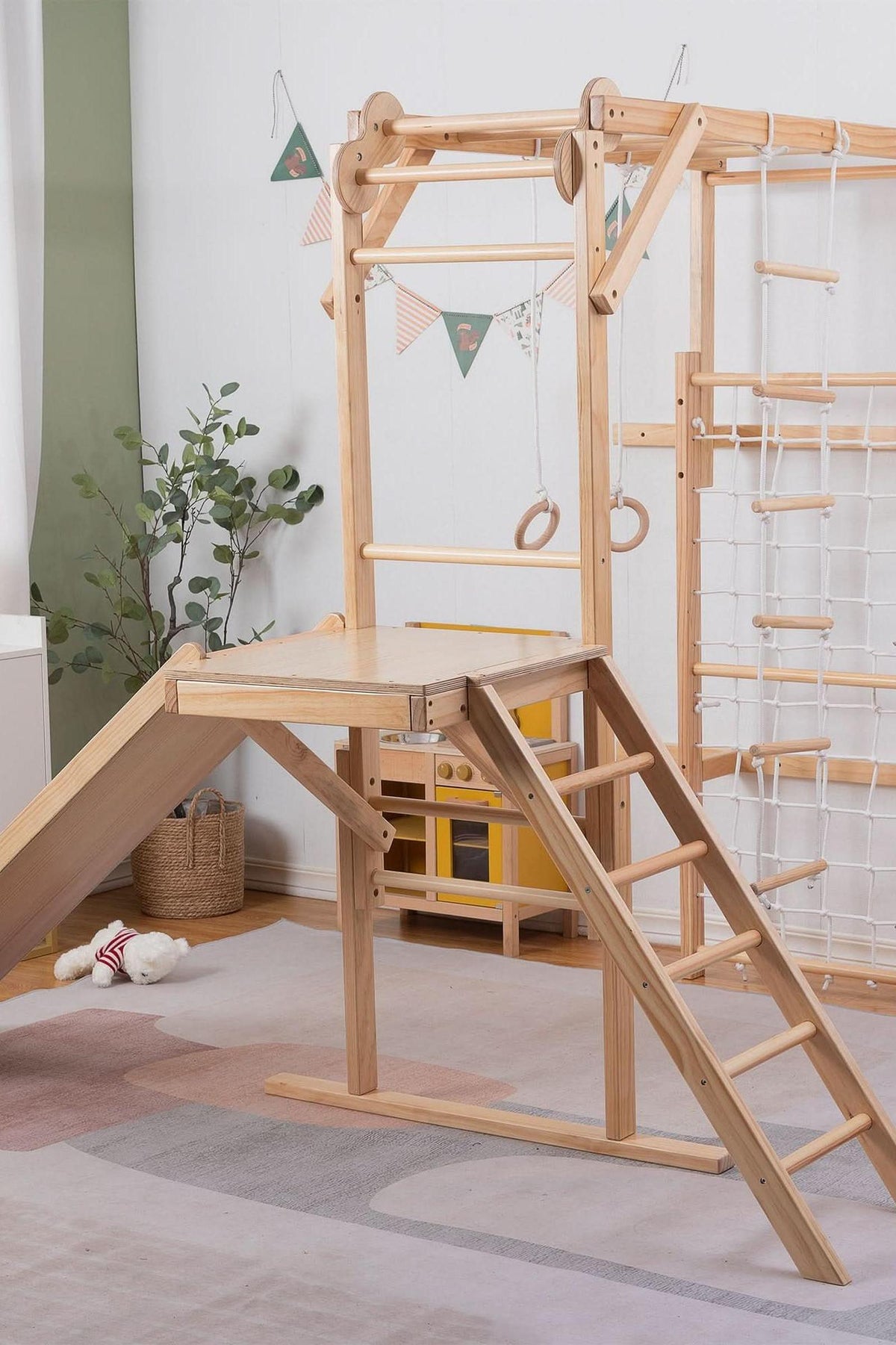 A wooden indoor jungle gym features a slide, climbing ladder, and hanging rings, designed for toddlers and kids. The natural wood finish complements the playful, eco-friendly atmosphere of the room.