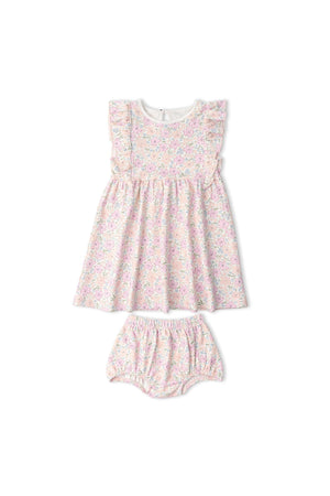 A floral-patterned organic cotton dress in soft pink hues, featuring flutter sleeves and a gathered waist, accompanied by matching bloomers. Ideal for baby girls, this outfit emphasizes sustainable fashion.