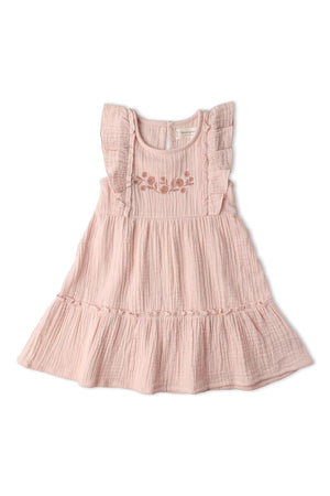 A blush pink organic cotton dress featuring delicate embroidery and soft tiers. The dress has ruffled straps, creating a charming, airy silhouette perfect for sunny-day adventures.