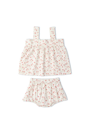 A soft, organic cotton scalloped top and matching bloomers set features a delicate floral print on a light background. This charming outfit is perfect for warm-weather days and young children.