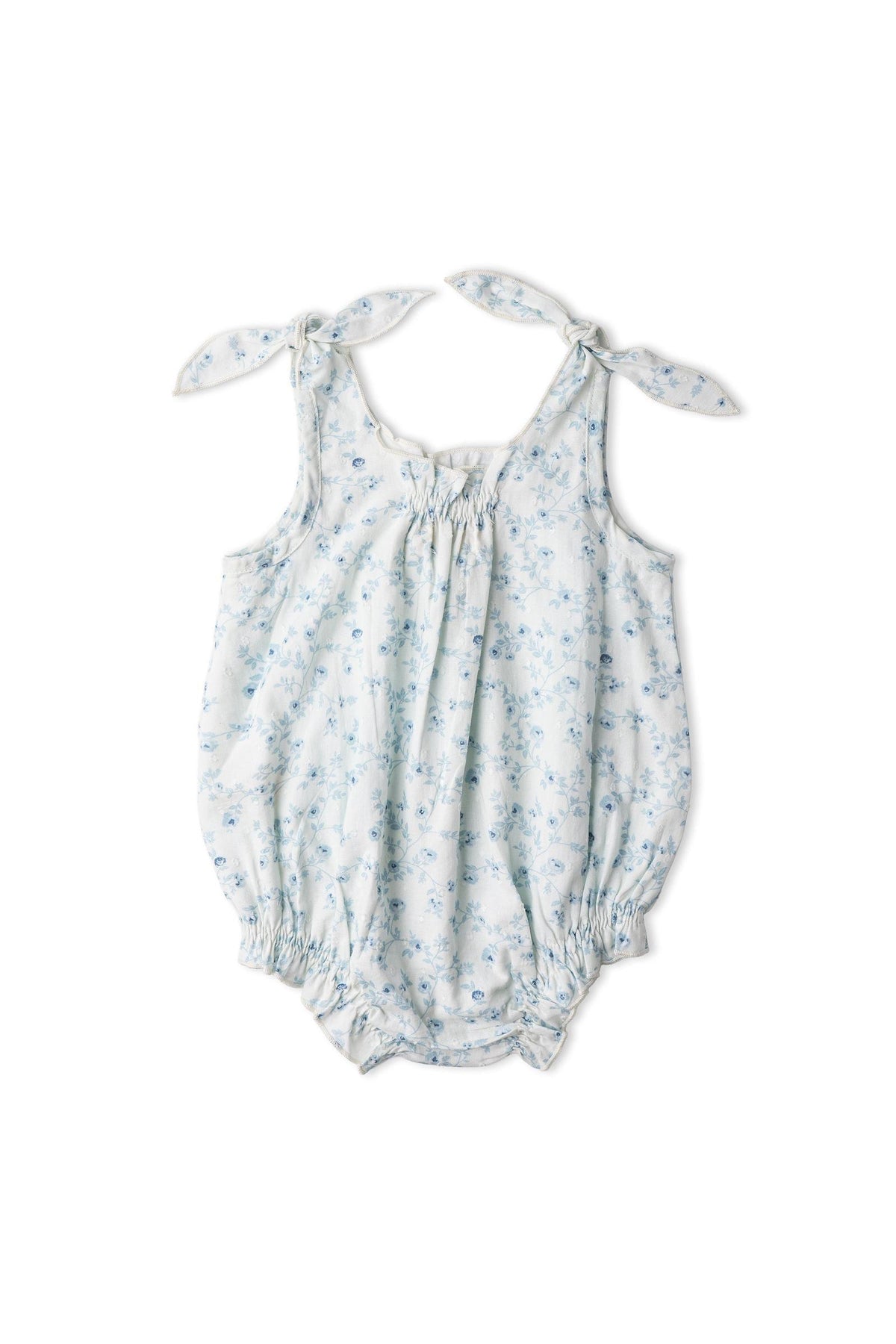 Organic bubble romper in a soft blue floral print, featuring adjustable tie shoulder straps and elasticized leg openings for a comfortable fit. Made from breathable organic cotton for gentle wear.