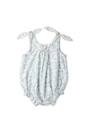 Organic bubble romper in a soft blue floral print, featuring adjustable tie shoulder straps and elasticized leg openings for a comfortable fit. Made from breathable organic cotton for gentle wear.