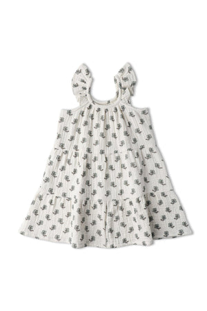 A light-colored, organic cotton dress featuring a tiered design with delicate floral patterns and ruffle straps. This playful dress is perfect for warm days and twirling adventures.