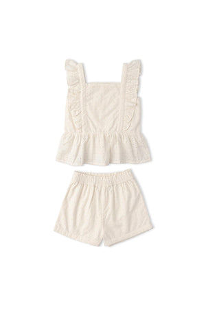 Organic cotton eyelet flutter top and shorts set in ivory, featuring delicate ruffles and intricate cutwork. Perfect for warm-weather outings, this charming outfit combines style with sustainability.