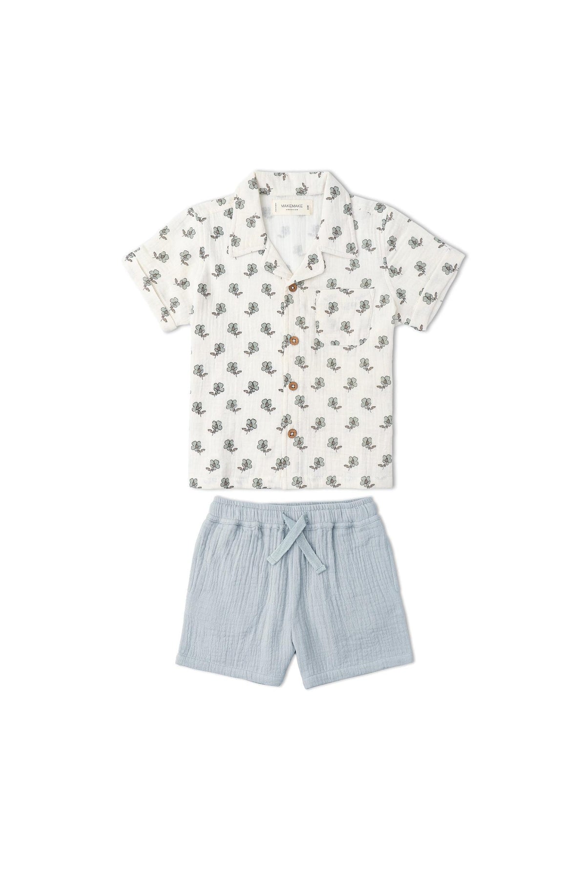 A lightweight, organic cotton shirt and shorts set for children, featuring a white shirt adorned with a subtle green leaf pattern and soft blue shorts, perfect for summer adventures.