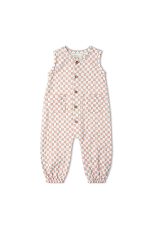 A soft muslin cotton jumpsuit in brick checks features a sleeveless design, delicate wooden buttons, and elasticized cuffs, perfect for comfortable wear and playful activities. Ideal for eco-conscious families.