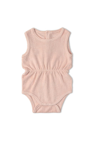 A soft, blush-colored organic cotton romper featuring a gently gathered waist. This sleeveless one-piece is designed for comfort and style in warm weather, perfect for little ones.