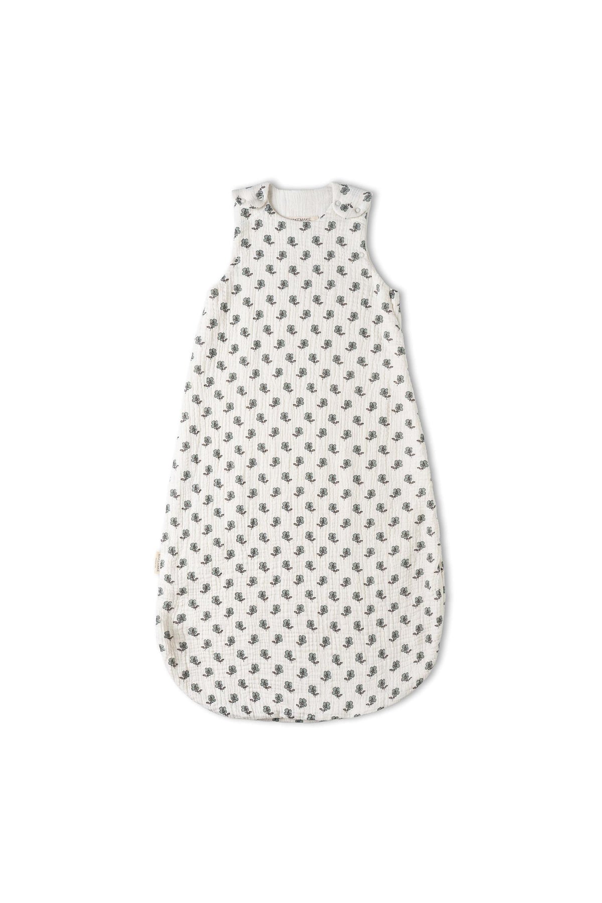A white organic cotton wearable blanket features a charming leaf print, designed for comfort and warmth. Its sleeveless style and breathable muslin material make it perfect for cozy sleep.