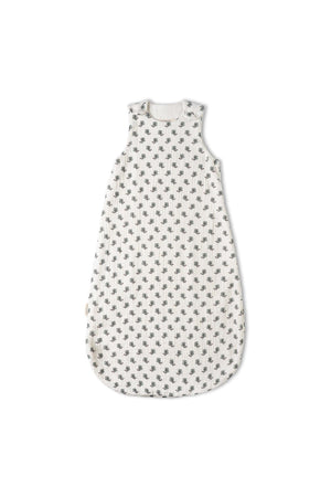 A white organic cotton wearable blanket features a charming leaf print, designed for comfort and warmth. Its sleeveless style and breathable muslin material make it perfect for cozy sleep.