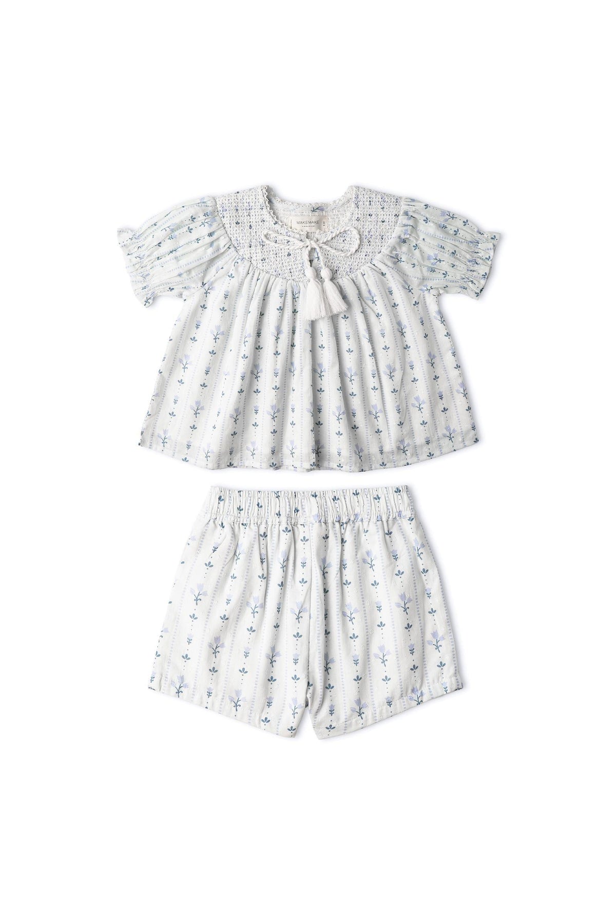 Light blue organic cotton smocked top and matching shorts set featuring delicate floral patterns and a textured weave. Ideal for sunny outings, combining comfort with playful style for children.
