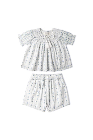 Light blue organic cotton smocked top and matching shorts set featuring delicate floral patterns and a textured weave. Ideal for sunny outings, combining comfort with playful style for children.