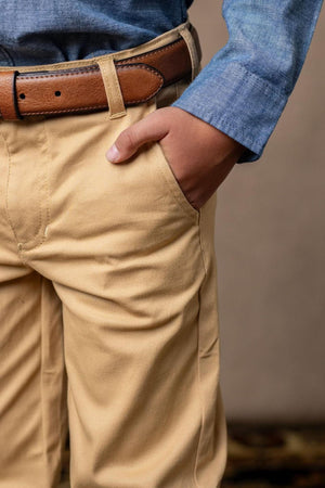 A close-up of khaki skinny chinos with a brown leather belt, featuring a hand in the pocket and a blue.