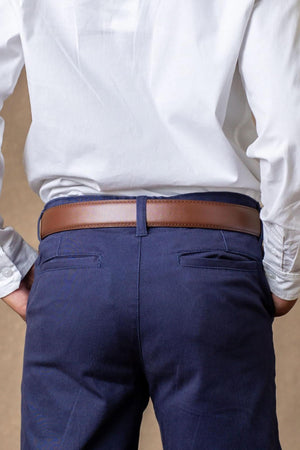 A person is wearing navy skinny chino pants with a brown belt, paired with a white long-sleeve shirt.