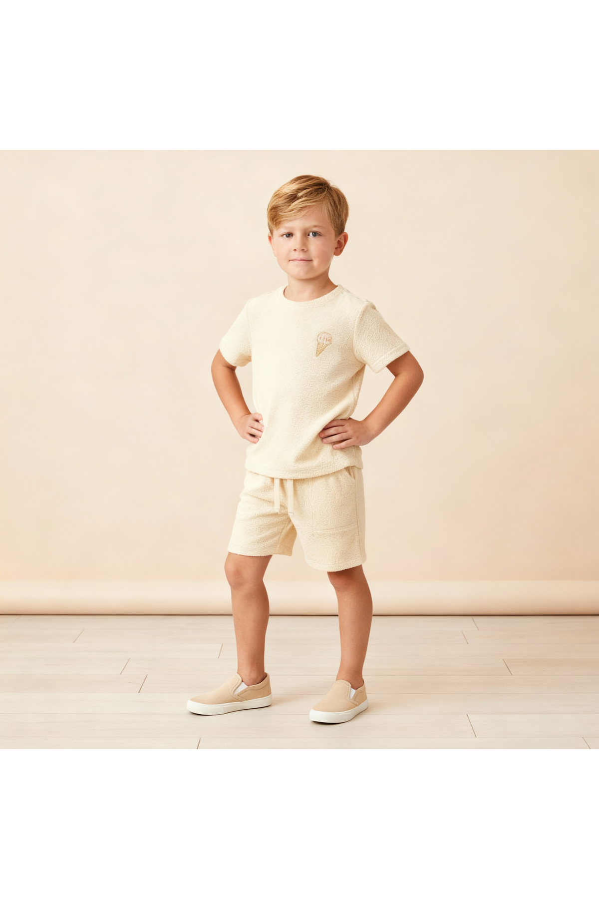 A young boy poses confidently in a soft, butter yellow organic terry tee and shorts set, featuring a relaxed fit and towel-like texture, perfect for summer comfort.