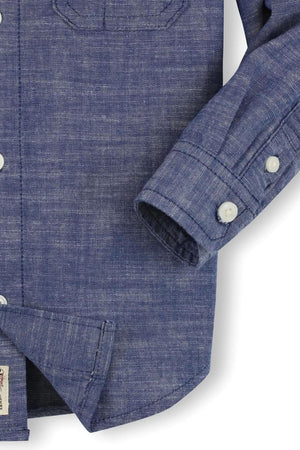 Close-up of a blue organic cotton button-down shirt for boys, featuring matte buttons and a classic chambray texture.