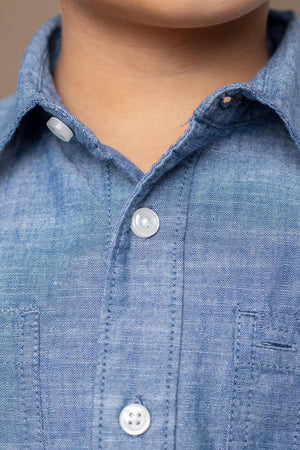 Close-up of a blue organic cotton button-down shirt featuring a classic collar, matte buttons, and subtle stitching details.