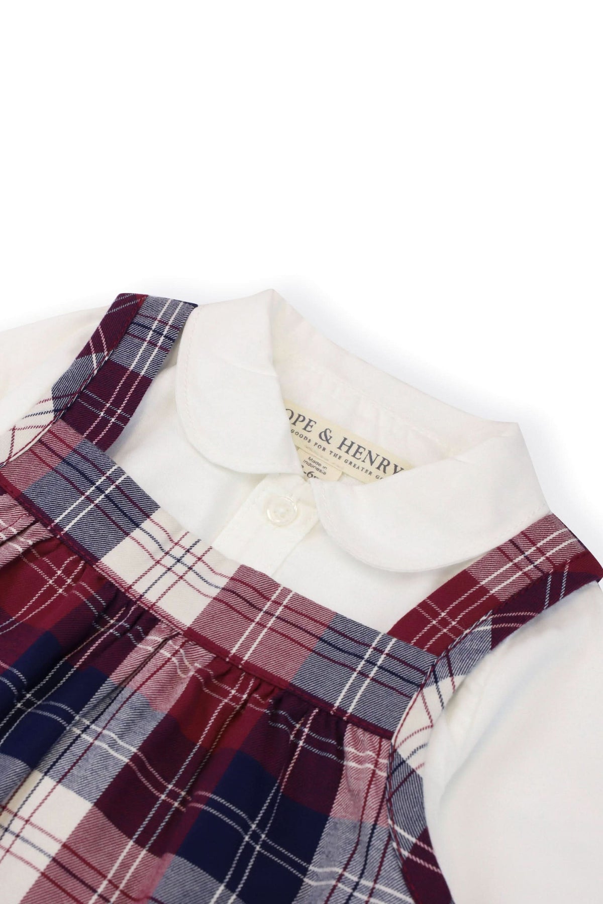 Close-up view of a Hope & Henry organic cotton bodysuit featuring a white Peter Pan collar, paired with a berry tartan plaid jumper, highlighting the vibrant colors and classic design.