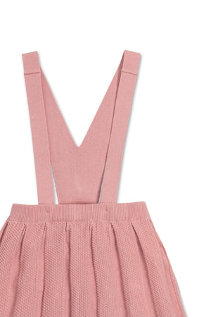 Close-up of a soft pink organic cotton overall skirt with pleated design and adjustable straps, ideal for toddlers and kids.