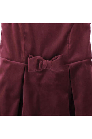 Close-up of a wine red jumper dress featuring a bow front detail and pleated skirt, made from soft organic cotton.