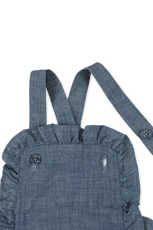 Close-up of a blue chambray ruffle sunsuit with adjustable straps and button detail, made from organic cotton for baby girls.