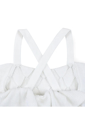 Close-up of a white organic cotton sweater romper featuring crisscross straps and delicate pointelle knit detailing. Perfect for baby girls.