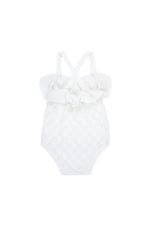 White organic cotton baby romper featuring ruffle detailing and cross-back straps, designed for easy dressing and comfort.