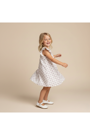 A young girl twirls in a short sleeve, lavender dress featuring a playful floral pattern. The dress is made from soft, breathable fabric, perfect for warm days and active play.