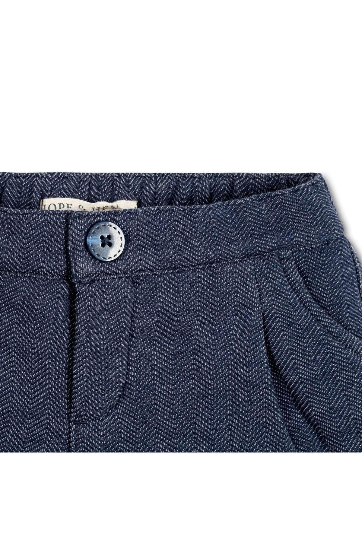 Close-up of navy blue dress shorts featuring a herringbone pattern, elastic waistband, and decorative button from Hope & Henry.