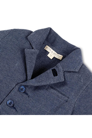 Close-up of a navy blue herringbone-patterned blazer by Hope & Henry, featuring faux leather buttons and a stylish collar.