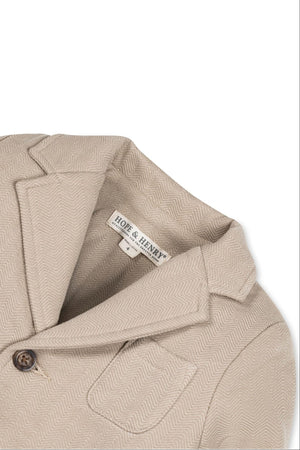 Close-up of a taupe cotton fleece blazer by Hope & Henry, featuring a herringbone pattern, faux horn button, and patch.