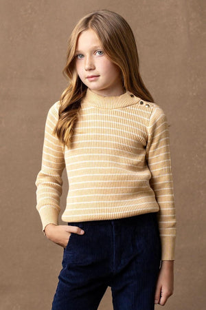 A young girl models a striped mock neck sweater in soft oatmeal and cream hues, featuring button details on the shoulder.